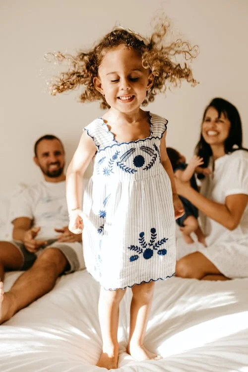 jeune fille avec cheveux crollés debout sur un lit