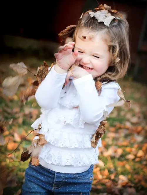 jeune fille qui joue avec des feuilles séchées