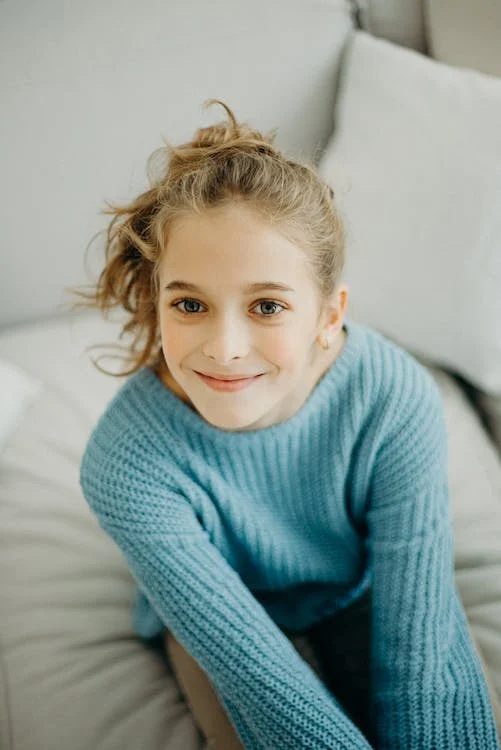 fille assisse sur un fauteuil qui sourit